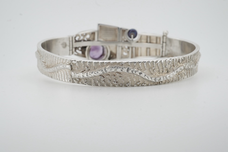 A contemporary silver and amethyst bangle, of abstract, Cubist-inspired design, to a textured band, set with a circular-cut amethyst and a cultured pearl, inner circumference approximately 20.8cm, maker's mark ZC, stampe